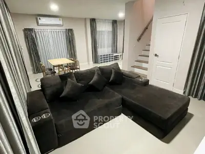 Modern living room with dark sectional sofa and dining area, featuring sleek curtains and minimalist design.