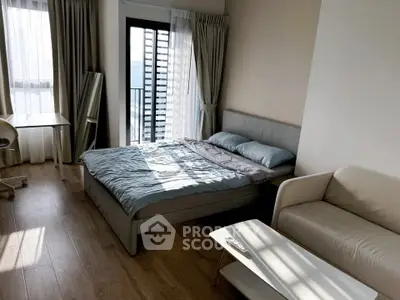 Modern bedroom with stylish decor, featuring a cozy bed, sleek sofa, and natural light from large windows.
