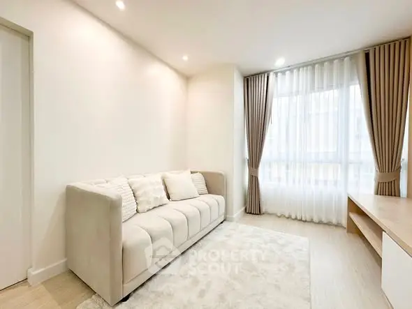 Bright and cozy living room with elegant sofa and large window, perfect for relaxation.