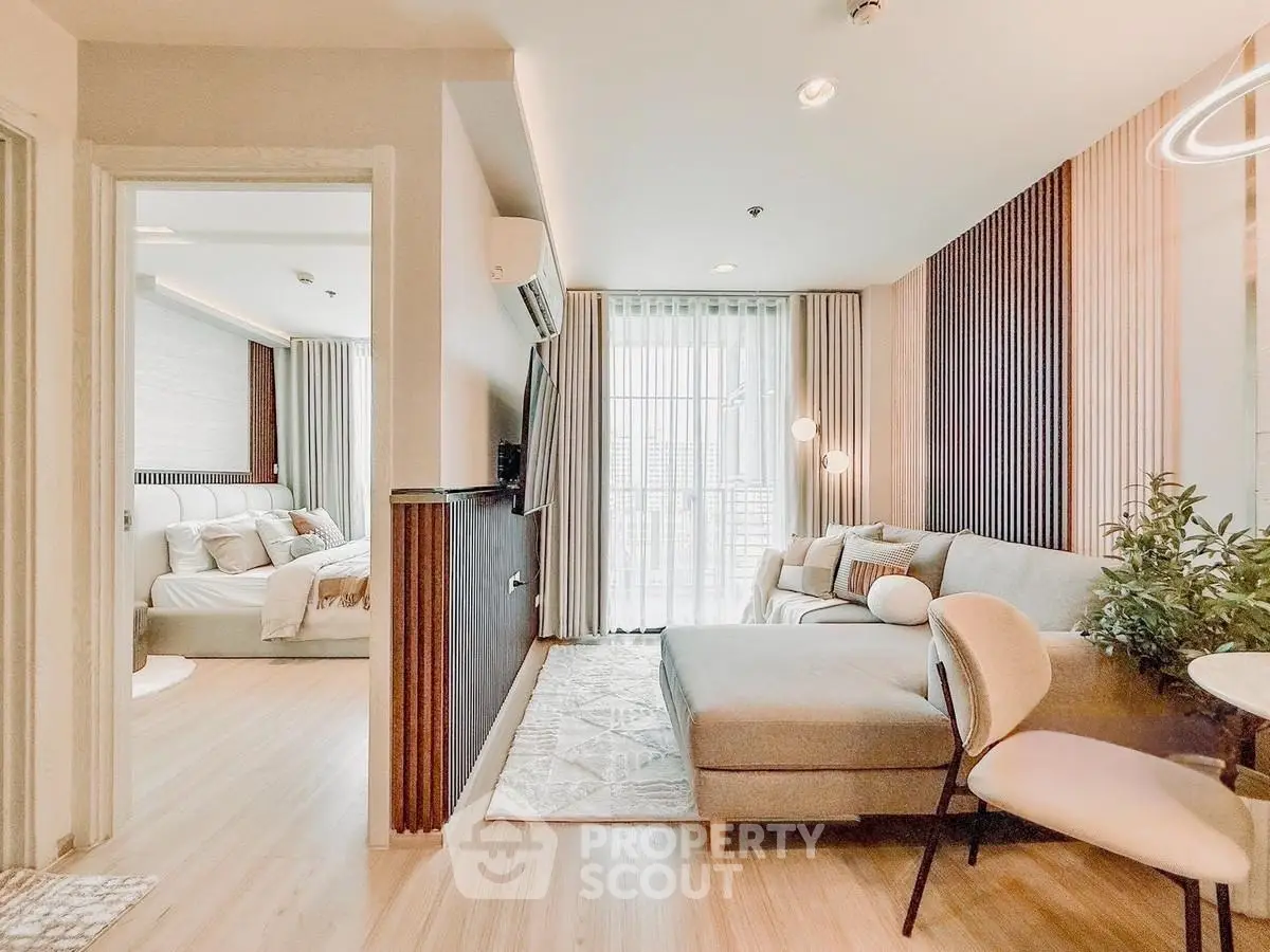 Stylish modern living room with cozy seating and elegant decor, leading to a bright bedroom with natural light.