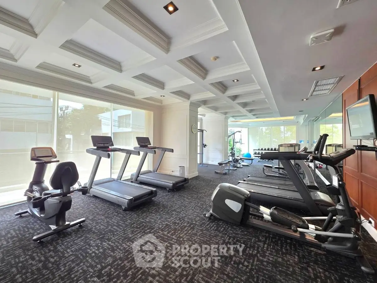 Spacious modern gym with state-of-the-art equipment and large windows for natural light.