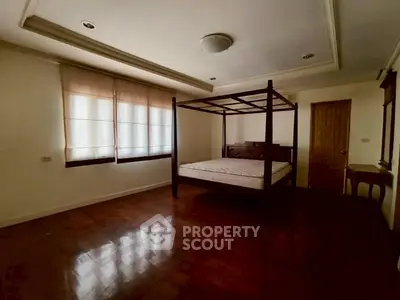 Spacious bedroom with elegant wooden flooring and canopy bed.
