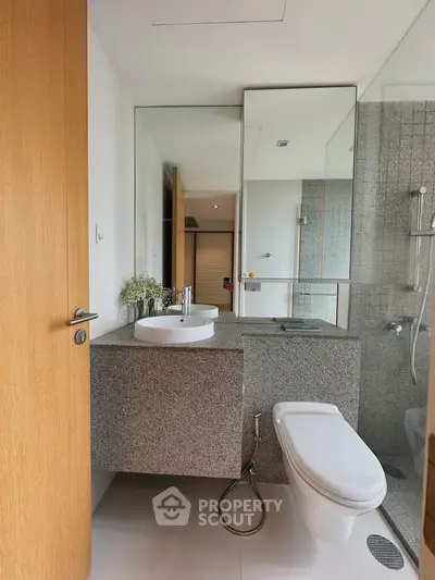 Modern bathroom with sleek design, featuring a floating vanity and glass shower enclosure.