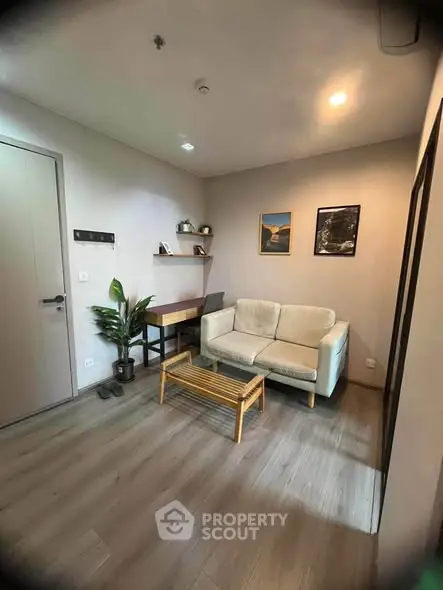 Cozy living room with modern decor and wooden flooring, featuring a comfortable sofa and stylish wall art.