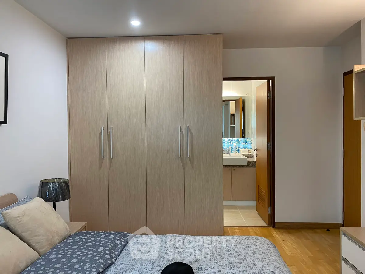 Spacious bedroom with modern wardrobe and ensuite bathroom in a stylish apartment.