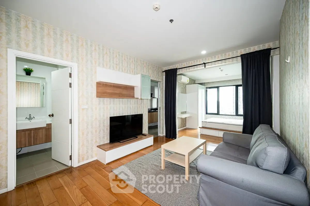 Modern living room with wooden flooring, cozy sofa, and open view to bedroom