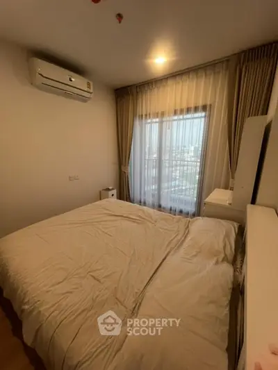 Cozy bedroom with large window and air conditioning in modern apartment