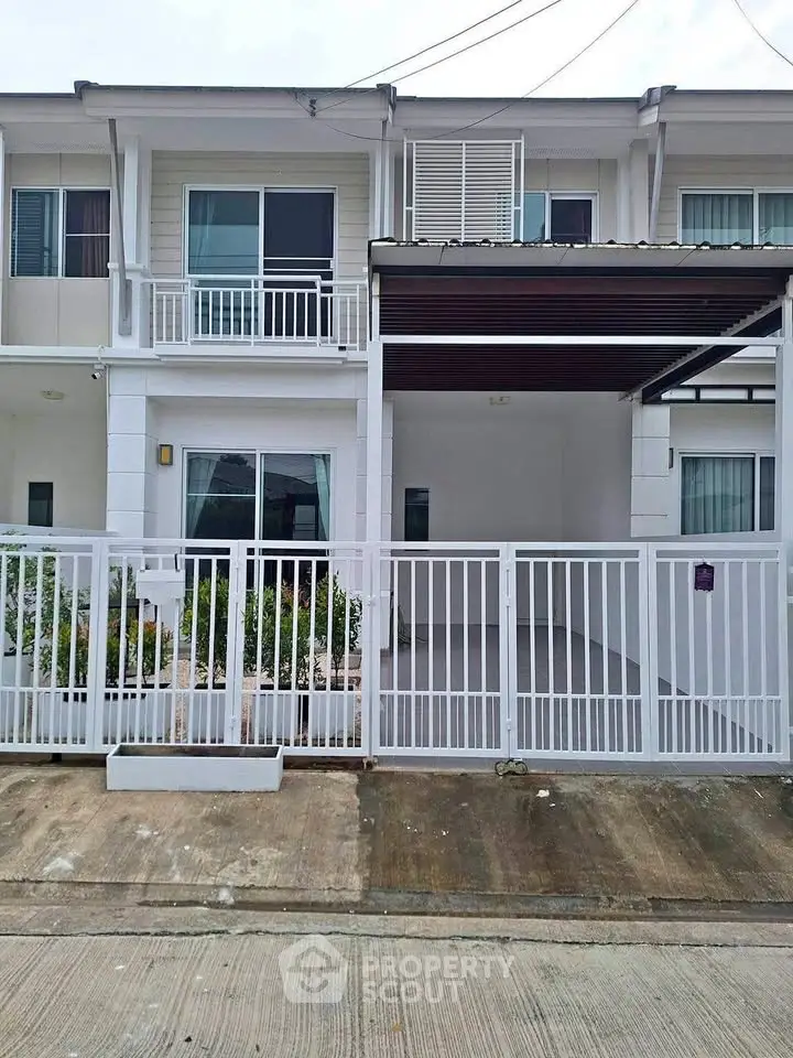 Modern townhouse exterior with gated entrance and balcony, perfect for urban living.