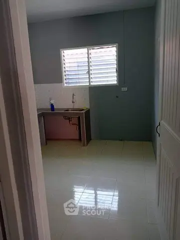 Spacious kitchen area with tiled floor and large window for natural light.