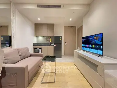 Modern living room with sleek furniture and smart TV, featuring a compact kitchen area and stylish decor.