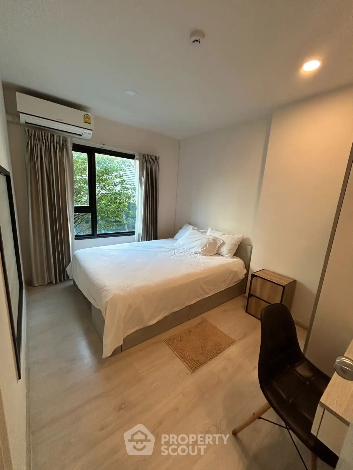 Cozy bedroom with large window and modern furnishings in a serene setting.