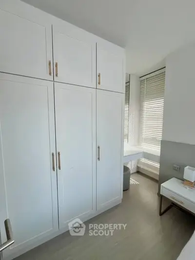 Modern bedroom with sleek white wardrobe and natural light