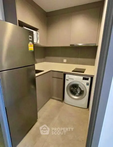 Modern compact kitchen with stainless steel appliances and washing machine
