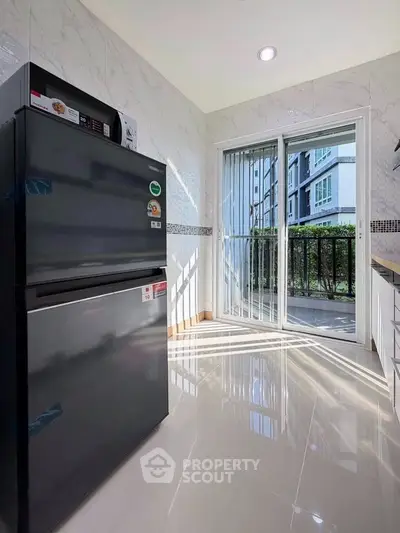 Modern kitchen with sleek black fridge and sliding glass door to balcony