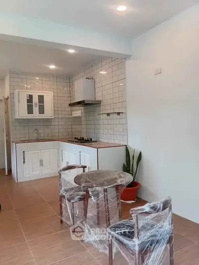 Modern kitchen with open layout and gas stove, featuring sleek white cabinets and cozy dining area.