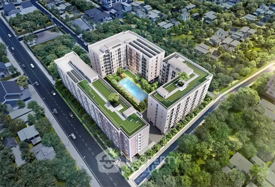 Aerial view of modern apartment complex with central pool and lush surroundings.