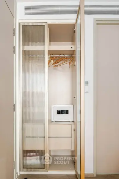 Modern apartment closet with safe and wooden hangers, sleek design