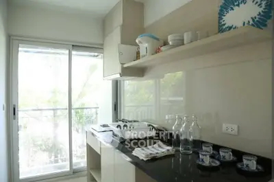Modern kitchen with sleek design and large window offering natural light