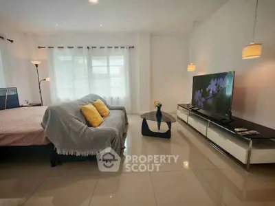 Spacious living room with modern decor and large TV, perfect for relaxation.
