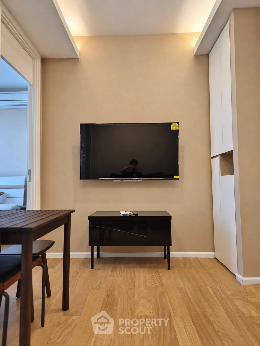 Modern living room with wall-mounted TV and sleek furniture in a cozy apartment.