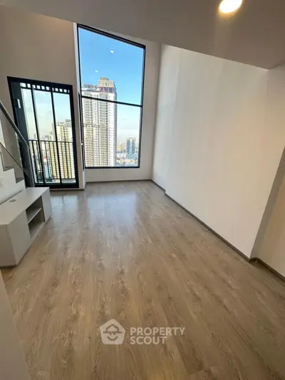 Spacious modern living room with large window and city view, perfect for urban living.