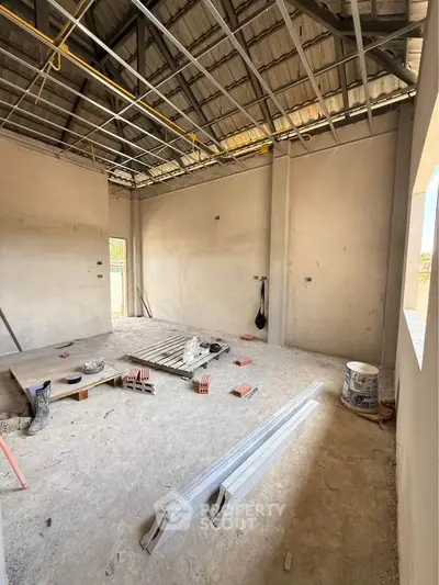 Under-construction room with exposed ceiling and building materials.