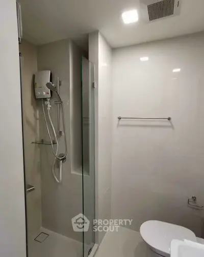 Modern bathroom with sleek shower and toilet in minimalist design.