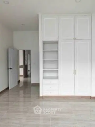 Spacious room with built-in white wardrobe and glossy tiled floor, perfect for modern living.