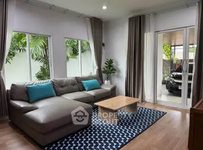 Spacious living room with modern decor and garden view, featuring a cozy sectional sofa and stylish rug.