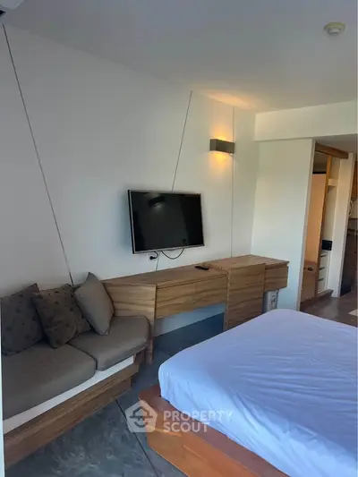 Modern bedroom with wall-mounted TV and stylish wooden furniture