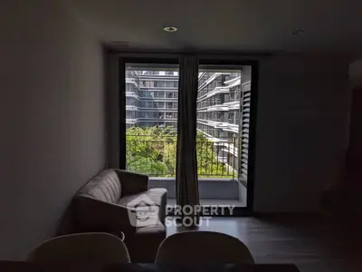 Modern apartment living room with balcony view of urban garden and contemporary architecture.