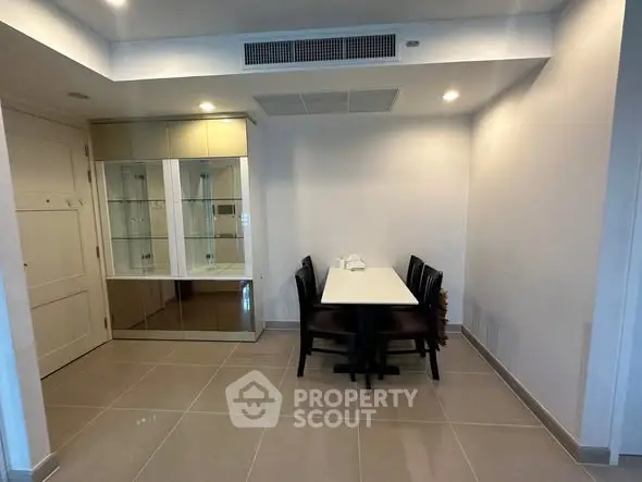 Modern dining area with sleek table and chairs, featuring built-in glass cabinet.