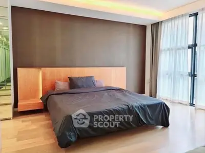 Spacious modern bedroom with large windows and wooden flooring