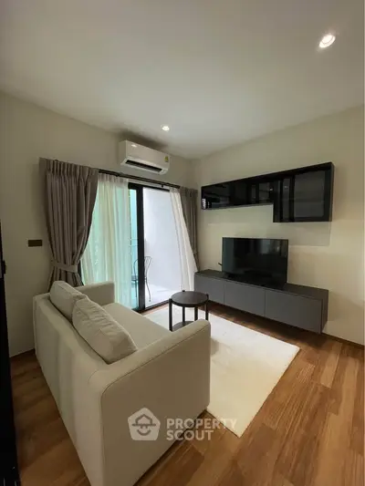 Modern living room with sleek furniture and balcony access, featuring a cozy sofa and wall-mounted TV.