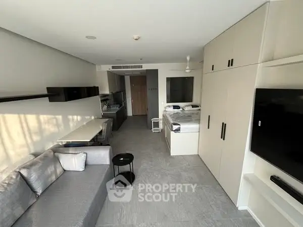 Modern studio apartment with sleek design and open layout, featuring a cozy living area and compact kitchen.