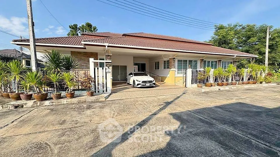 Charming single-story home with spacious driveway and lush potted plants, perfect for family living.