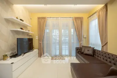 Modern living room with elegant decor, large TV, and natural light through sheer curtains.