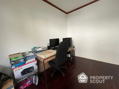 Cozy home office with desk, chair, and computer setup on wooden flooring.