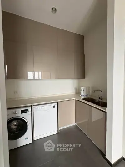 Modern kitchen with sleek cabinetry, washing machine, and dishwasher in a compact layout.