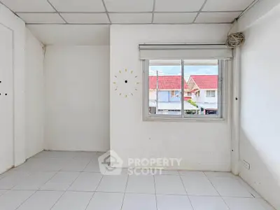 Bright empty room with tiled floor and large window overlooking colorful houses.