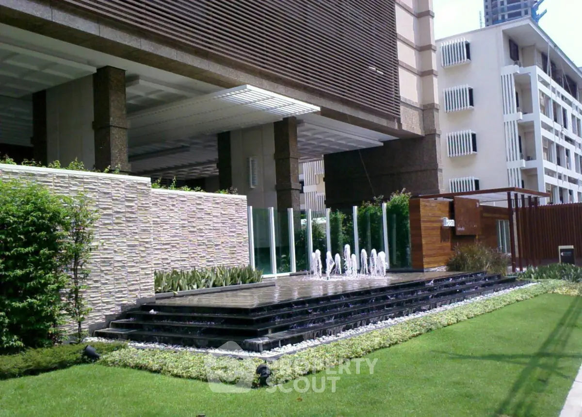 Luxurious building entrance with modern water feature and lush landscaping