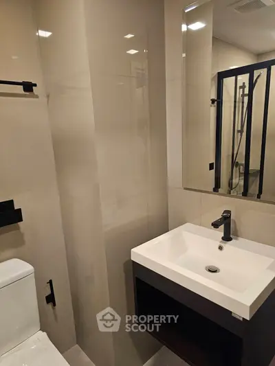Modern bathroom with sleek fixtures and elegant design, featuring a stylish sink and mirror.