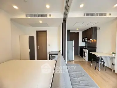 Modern studio apartment with open layout, featuring kitchen and living area with sleek design.