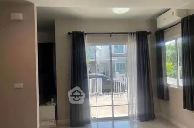 Bright living room with large window and modern curtains overlooking a sunny patio.