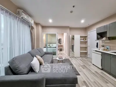 Modern open-layout living room with stylish gray sofa and sleek kitchen area