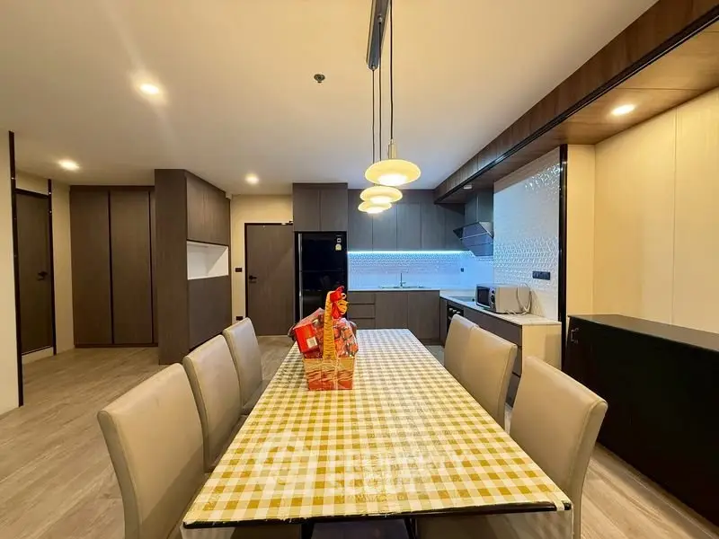 Modern kitchen with dining area featuring sleek cabinets and stylish lighting.