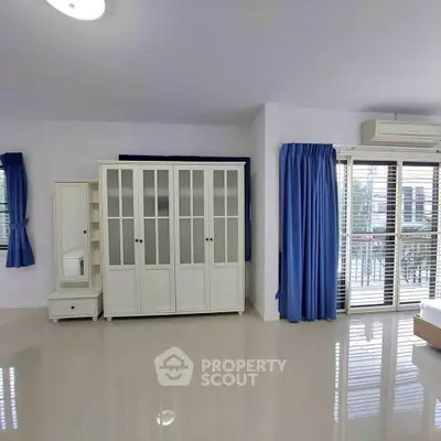 Spacious bedroom with large wardrobe and balcony access, featuring elegant blue curtains and ample natural light.