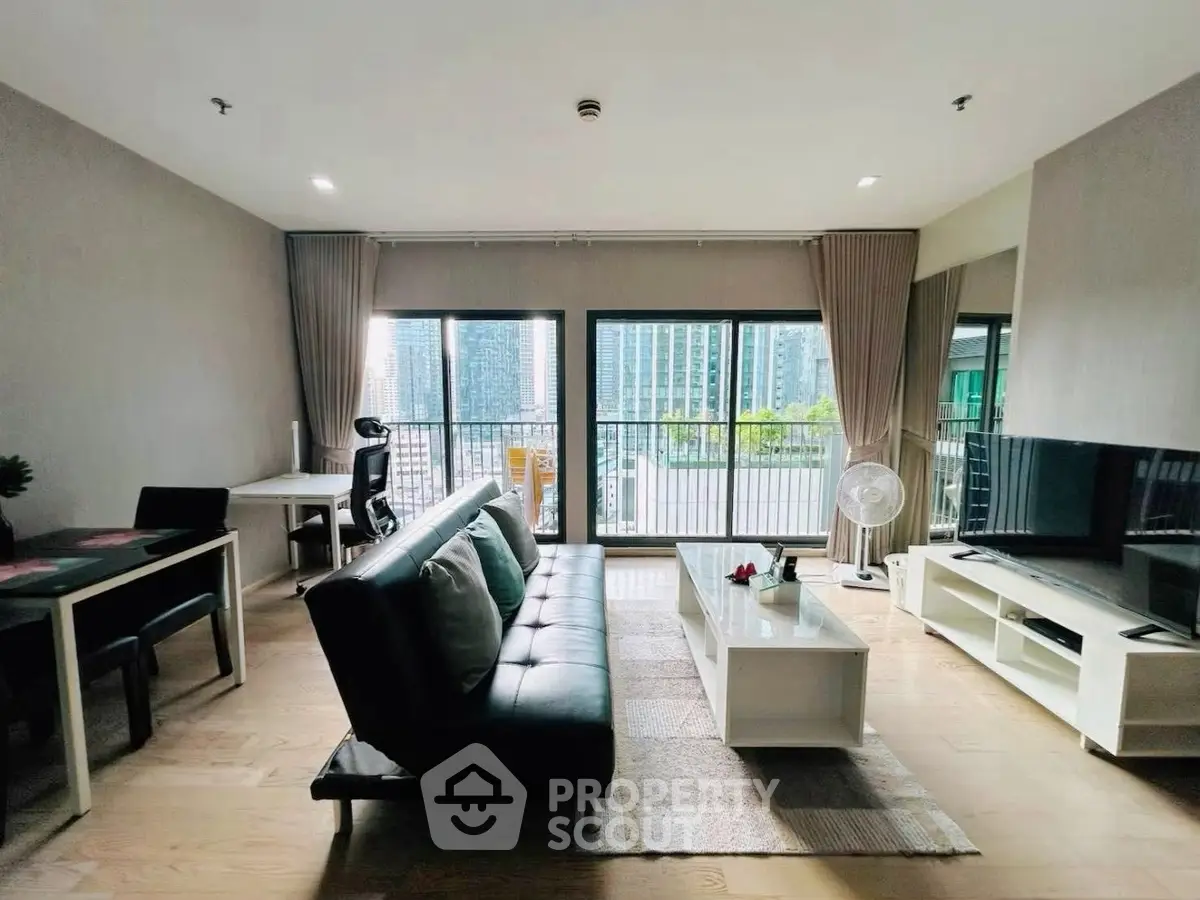 Spacious modern living room with city view, featuring sleek furniture and abundant natural light.