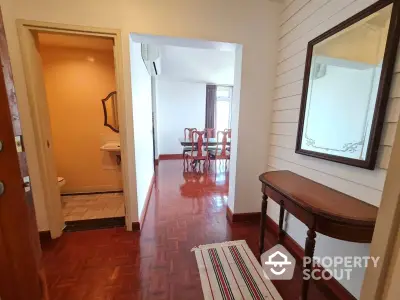 Charming entryway with elegant wooden flooring and classic furniture leading to a bright dining area.