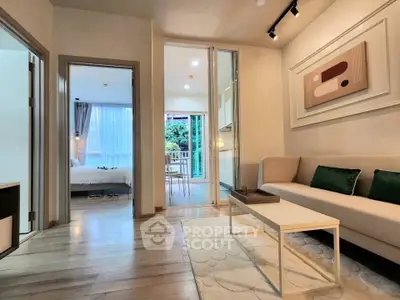 Modern living room with elegant decor and view into a cozy bedroom, featuring stylish furniture.